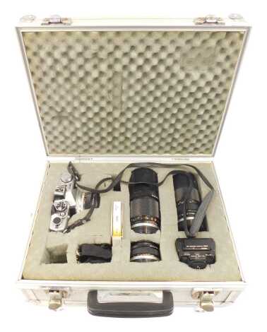 An Olympus OM-2 camera, together with lens' to include f=200mm, flash, etc., in a metal case.