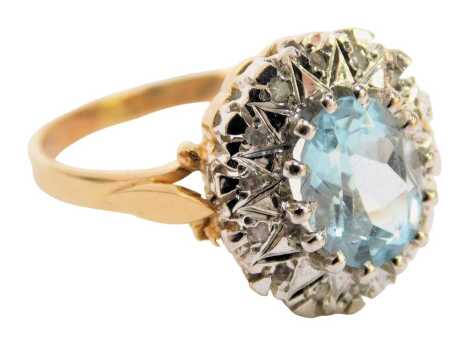 An aquamarine and diamond dress ring, the oval aquamarine in a claw setting, surrounded by pave set tiny diamonds, in white gold, on a yellow gold band, unmarked, ring size P½, 3.6g all in.