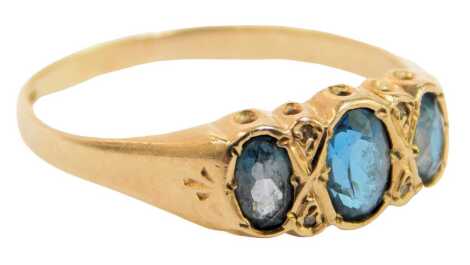 A 9ct gold and blue topaz dress ring, set with three oval blue topaz, in a rub over setting, with four tiny diamond chips, and fan design shoulders, ring size T½, 2.2g all in.