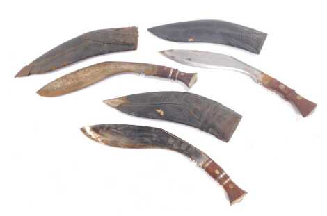 Three Nepalese or Indian kukris, each with wooden handle, with metal inlay, with leather scabbards.