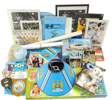 A group of Manchester City and other footballing ephemera, to include football programmes, pictures, limited edition prints bearing biro signature, scarves, emblems, pin badges, posters, etc. (3 shelves)