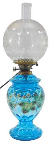 A Victorian oil lamp, with frosted and clear glass globular shade decorated with flowers, with a blue glass base decorated with flowers and leaf in coloured enamels, converted to electricity, with chimney, 60cm high overall.