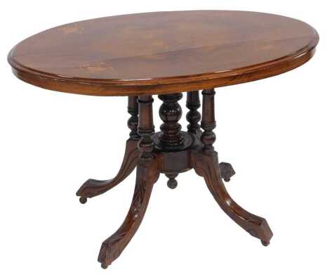 A 19thC walnut and inlaid tilt top table, the oval top with stylised flower inlay, on five turned supports, with out swept carved legs, on castors, 70cm high, the top 71cm x 102cm.