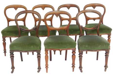 A set of five Victorian mahogany balloon back dining chairs, each with a shaped solid seat upholstered in green draylon fabric, on turned legs, and two similar. (7)