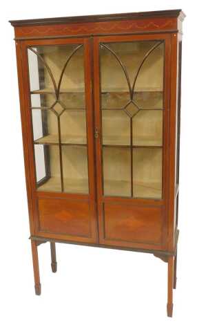 An Edwardian mahogany and inlaid display cabinet, moulded top with bow and swag inlaid decoration above astragal glazed and panelled doors enclosing three shelves, on splayed legs, 167cm high, 93cm wide, 31cm deep.