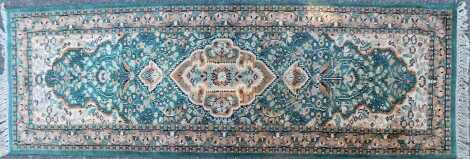 A Persian style green ground rug, with central medallion surrounded by flowers within one wide and two narrow borders, 187cm x 62cm.