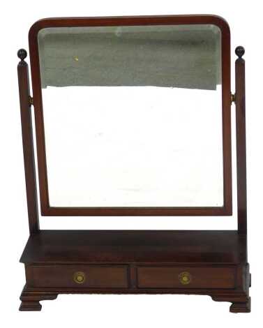 An early 20thC mahogany swing frame toilet mirror, inset bevel glass, raised on a base with two frieze drawers, on ogee bracket feet, 78.5cm high, 64.5cm wide, 32cm deep.