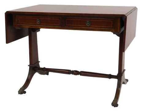 A 20thC mahogany and line inlaid Regency style sofa table, the drop leaf top above two frieze drawers, line carved end supports, out swept feet united by a turned stretcher with lion paw capped feet on castors, 75cm high, 100cm wide, 150cm extended, 61cm 