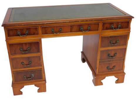 A late 20thC yew pedestal desk, the top with a moulded edge with a green tooled leather inset above an arrangement of seven drawers, on bracket feet, 79cm high, 122cm wide, 60cm deep.