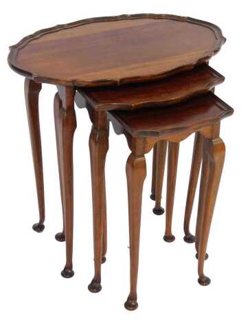 A nest of three mahogany tables, each with an oval piecrust top, on cabriole legs with pad feet, the largest 60cm high.