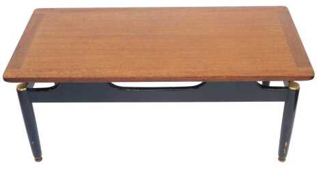 An EG Gomme teak coffee table, rectangular top on a painted black base, on cylindrical tapering legs and brass feet, 39cm high, the top 99cm x 48cm.