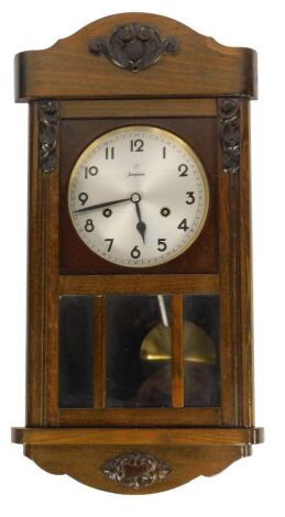 A Junghans oak cased wall clock, the arched top with raised and carved scroll with silvered numeric dial, eight day movement, with coil strike, 48cm high, 26cm wide, 14cm deep.