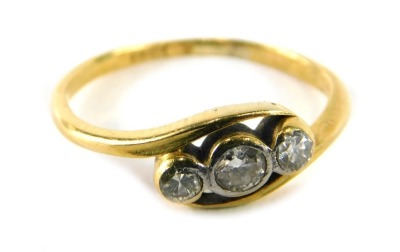 A three stone diamond twist ring, set with three round brilliant cut diamonds, each in rub over setting, on a yellow metal band, marked 18ct, ring size H½, 1.7g all in.