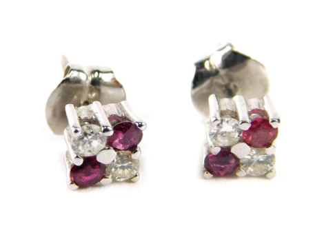 A pair of ruby and diamond stud earrings, each set with two round brilliant cut diamonds approx 0.05cts and two rubies, in white gold setting, unmarked, 2g all in.