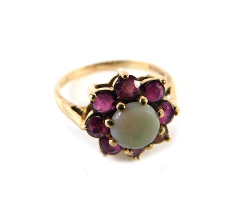 A 9ct gold cluster ring, set with seven garnets and centred by an opal, in a raised basket setting, ring size P, 2.5g all in.