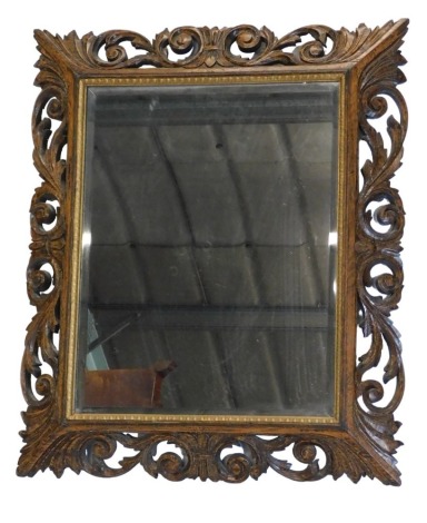 An early 20thC carved oak wall mirror, with rectangular bevelled plate, 85cm high, 72cm wide.