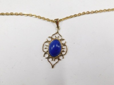 A 9ct gold lapis pendant and chain, the shaped pendant with oval lapis and pierced scroll outer border, on a fine link gold plated neck chain, the pendant 2.5cm high, 4.1g all in. - 2