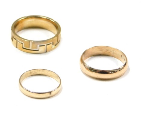 Three various dress rings, comprising a 9ct gold wedding band, of plain design, a wedding band stamped 375, and a Greek key border band stamped 9kt, 9.6g all in. (3)