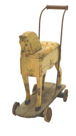 A late 19th/early 20thC cream and dapple painted child's push along horse, on rectangular base, with solid metal wheels, 59cm long.