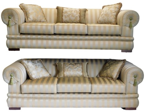 A pair of large Duresta style sofas, each with gold and silver coloured striped fabric, rope braided borders and tassels to the scroll ends, 232cm wide. The upholstery in this lot does not comply with the 1988 (Fire & Fire Furnishing) Regulations, unless 