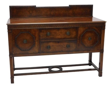 An early 20thC walnut sideboard, with a raised back, the base with a moulded edge above a blind fret frieze, with an arrangement of two drawers and two doors, on reeded supports, with flat stretcher, stamped and labelled Waring & Gillow Ltd to top drawer.