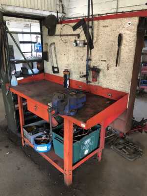 A red steel tray top work bench, with drawer, undershelf and vice, and backed with parts bins, 150cm wide, the tray 65cm deep plus 20cm of bay.