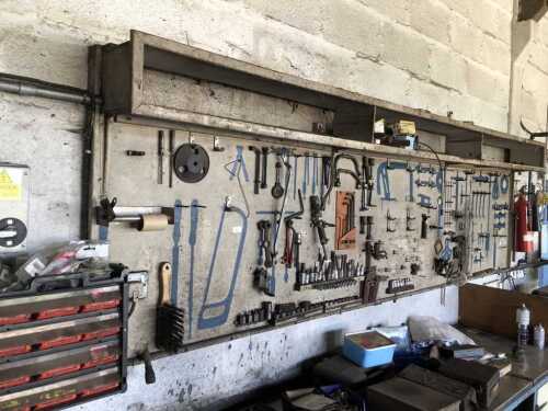 A wall mounted tool rack, with some tools and parts bins.