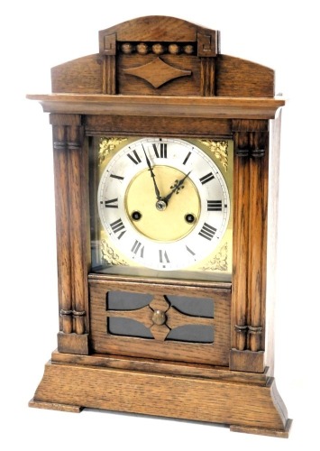 A late 19thC German oak cased mantel clock, square brass dial with floral spandrels, silvered chapter ring bearing Roman numerals, eight day HAG movement, with coil strike, the case of architectural form, with pendulum, and key, 41cm high.