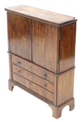A Georgian mahogany apprentice linen press, the outswept pediment over a pair of doors opening to reveal two shelves above three drawers, over three long drawers, raised on bracket feet, 72.5cm high, 59.5cm wide, 20cm deep.