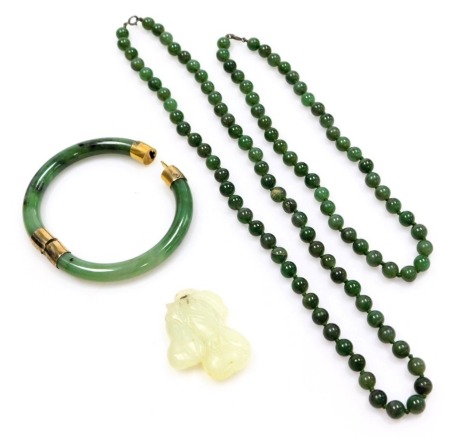 A jade bangle, with gilt metal snap clasp and mounts, stamped 925, two strings of jade beads, and a jade pendant formed as two gourds.