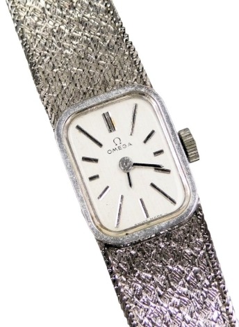 An Omega lady's 9ct white gold cased wristwatch, oblong dial with white batons, movement number 328074, on a mesh bracelet strap, with certificate, boxed, 21.6g all in.