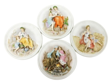 A set of four late 19thC Parian plaques, relief moulded with figures, emblematic of the four seasons, 29cm diameter.