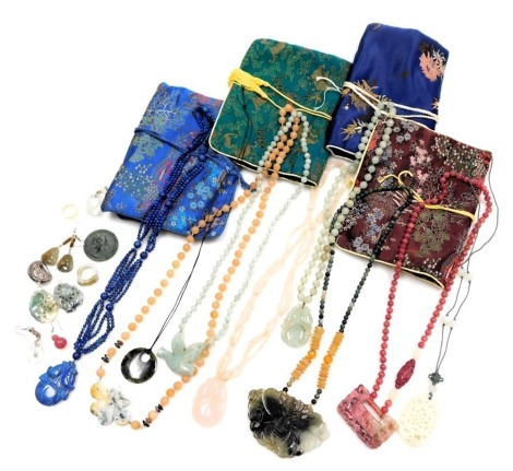 A group of Chinese jade and hardstone pendants, strings of beads, a ring, and jewellery pouches.