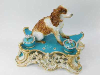 A 19thC Jacob Petit (Fontainebleau) porcelain inkstand, of scrolling and floral encrusted form, in blue and white with gilt highlights, surmounted by figure of a Spaniel, with two porcelain lidded inkwells, signed JP, 30cm high. (AF) - 2