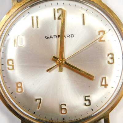 A Garrard 9ct gold cased gent's wristwatch, the silvered numeric dial with gold hands, in case stamped Vickers, inscribed LT Payne, January 1978 with Thirty Four Years Service, on black leather strap, the dial 2.8cm diameter, 30g all in. - 2