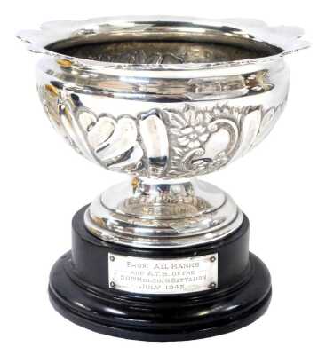 An Edward Vii silver pedestal bowl, with a frilled rim, embossed floral and foliate decoration, on a stepped circular foot, Birmingham 1904, 10.10oz, on a socle with a presentation plaque.