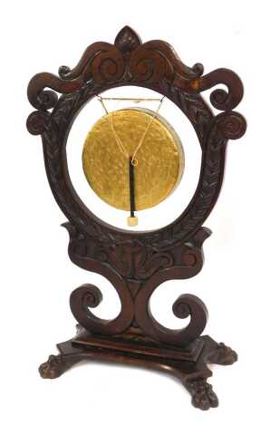 A Victorian oak and brass table gong, the large frame carved with leaves and scrolls, with brass central gong, on a rectangular base with claw feet, 125cm high, 80cm wide, 36cm deep.