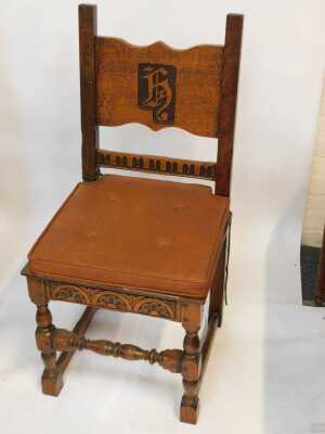 A set of four 20thC oak armchairs, comprising carver and three singles, each with carved and raised back bearing initials/shield possibly H, with later cushions. (4) - 3