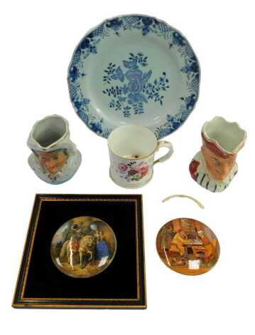 An 18thC blue and white tin glazed earthenware plate, decorated with flowers, 25.5cm wide, together with a pair of Victorian Punch and Judy pottery jugs, 11cm high, two Prattware pot lids, one framed, etc. (1 tray)