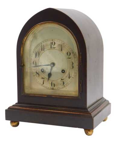 An early 20thC mahogany cased mantel clock, the silvered dial bearing Arabic numerals, Junghans eight day movement with coil strike, the case of domed form, on a moulded base raised on four feet, 30cm high.