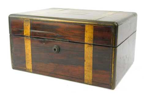 A Victorian rosewood and brass bound dressing table box, the hinged lid enclosing a crushed red velvet interior, with drop down top, the base with various recesses containing an assortment of dressing table bottles, the box 30cm wide.