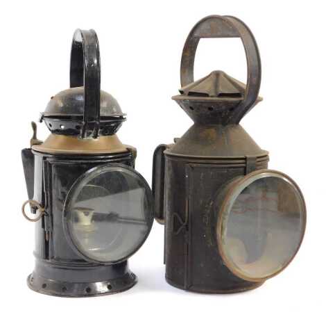 Two similar railway lamps, each in black painted cast metal with ring handles, 31cm high and 33cm high.