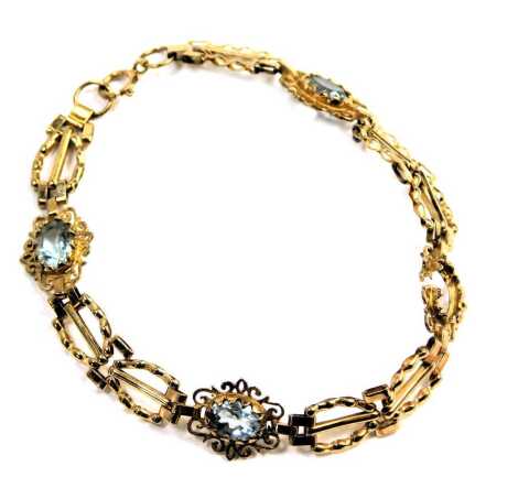 An aquamarine bracelet, set over four floral sections, each with an oval aquamarine and patterned outer border, yellow metal stamped 375, 17cm wide, 5.8g all in. (AF)