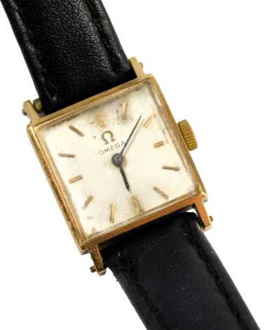 An Omega 9ct gold cased lady's wristwatch, the square watch head with silvered dial and blue hands, 1.5cm diameter, on a thin black leather strap, 12.1g all in, with Omega information pouch.