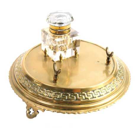 A Victorian brass desk stand, with a cut glass inkwell, on a circular pierced base, pen rest, on four outswept feet, 11cm high, 18cm wide.