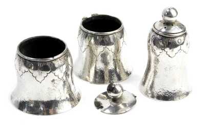 A Chinese white metal cruet, comprising pepper pot, open salt, and a further lidded pot, each of hammered bell-shaped form with leaf band, 2.47oz. (1 AF)