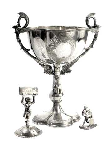 Silver plated wares, comprising a 20thC silver plated goblet, with foot in flight stem and dragon moulded handles, on four fold petalated base, 23cm high, a silver plated menu stand, 9cm high, and a white metal camel place stand, 4cm high. (3)