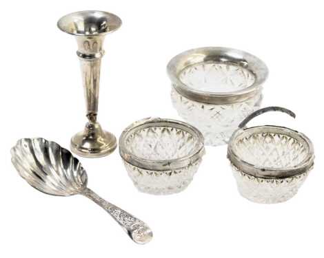 Three silver rimmed and cut glass salts, a miniature silver trumpet vase, 0.54oz gross, and a silver plated fluted caddy spoon. (5)