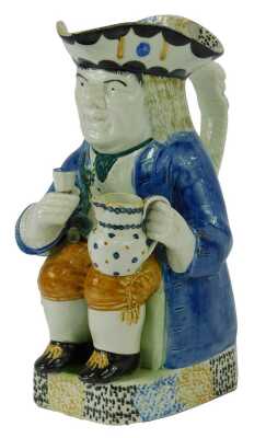 An early 19thC pearlware Toby jug, modelled as a seated gentleman in a tricorn hat holding a jug in one hand and goblet in the other, 27cm high.