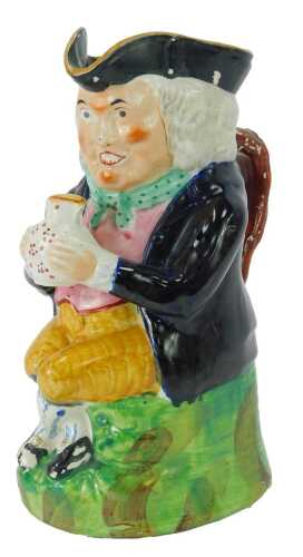 A 19thC pottery Toby jug, modelled as a seated gentleman in tricorn hat grasping a jug in two hands, 23.5cm high.